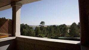 A balcony with a view of a forest and a distant tree. - Hotel Abeiras (O Grove)