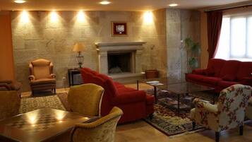 A cozy living room with a fireplace, red sofas, a coffee table, and a chess table.