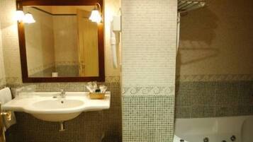 A bathroom with a sink, mirror, and bathtub.