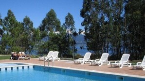 A pool area with lounge chairs and a view of the ocean. - Hotel Abeiras (O Grove)