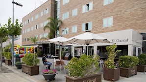 A restaurant named El Garxal with outdoor seating, potted plants, and a brick building facade. - Hotel Rull (Deltebre)