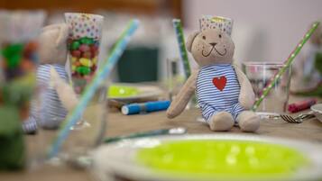 Een tafel met een teddybeer, een glas met snoepjes en een groen bord.