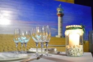 Una mesa dispuesta con copas de vino, una vela y un frasco decorativo.
