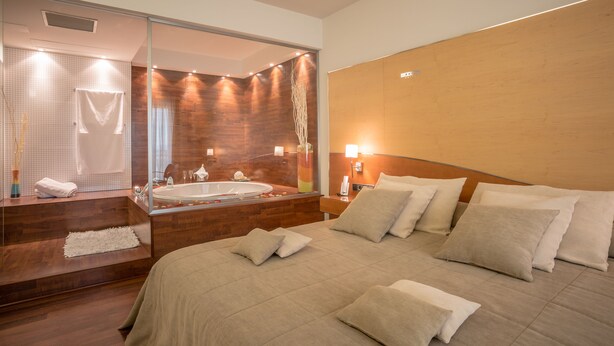 A modern hotel room with a large bed, a separate bathroom with a bathtub, and a large mirror. - Hotel Rull (Deltebre)