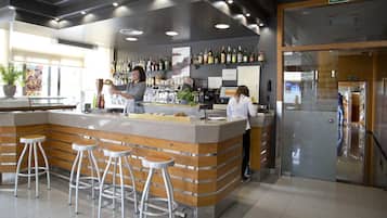 A modern bar area with a counter, stools, and a variety of bottles.
