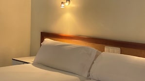A hotel room with a neatly made bed, a wooden headboard, and a wall-mounted light fixture. - Laguna Park 2 (Adeje)