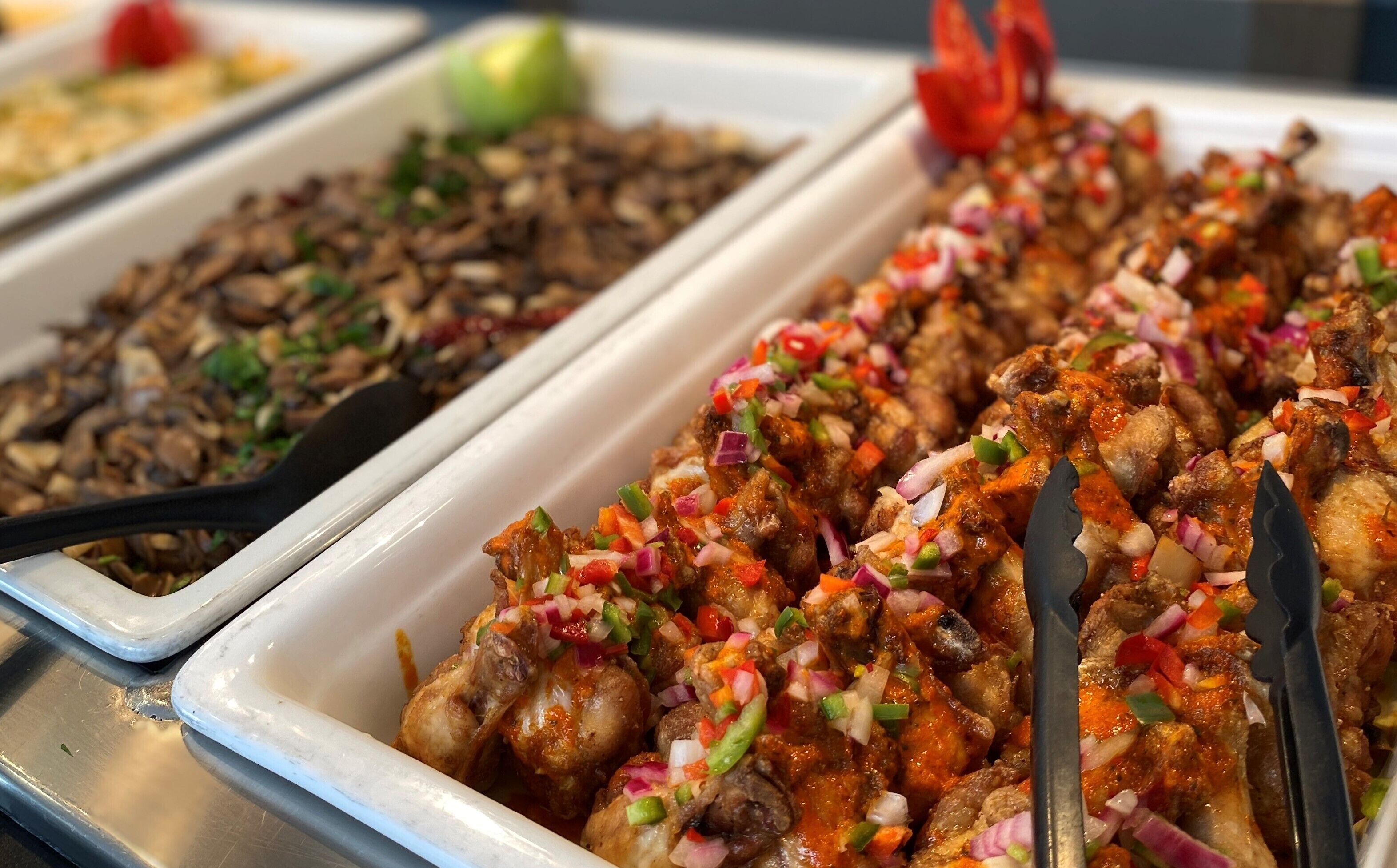 Een buffet met diverse gerechten, waaronder een hoek met rode saus en blokjes groenten, en een ander deel met suggestief gefrituurde snacks.