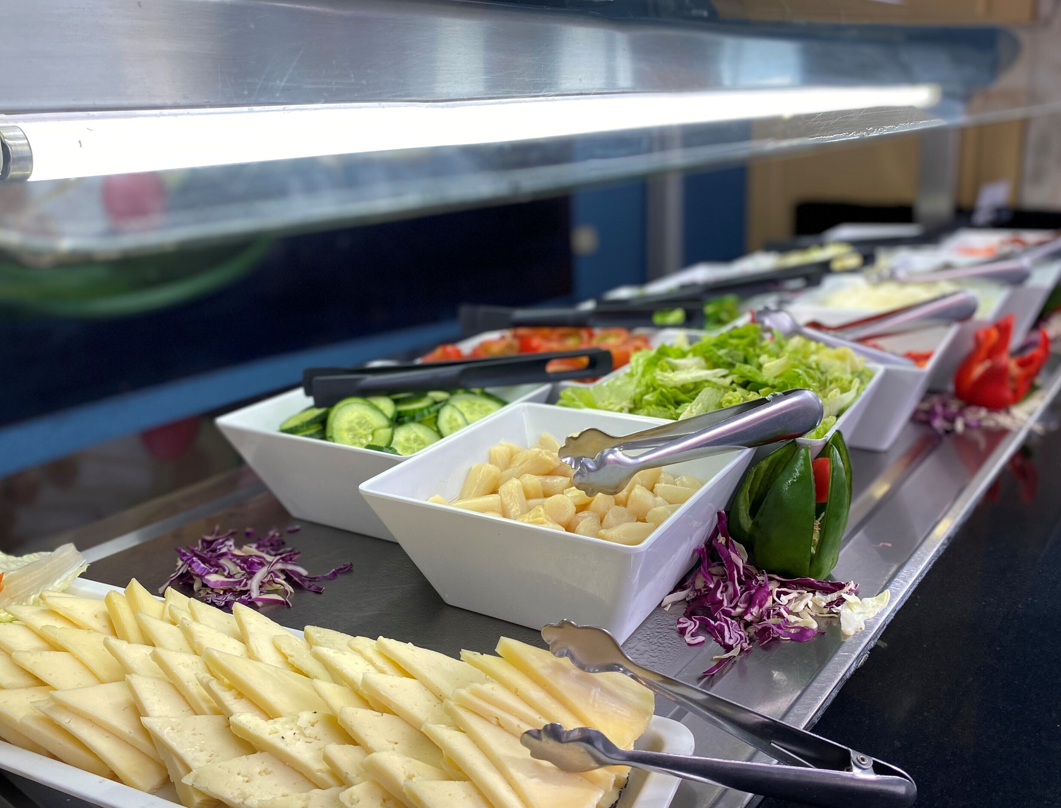 Un buffet con diverse pietanze, tra cui formaggio a fette, cetrioli e verdure.