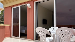 A hotel room with a sliding glass door leading to a balcony with white plastic chairs and a small table. - Laguna Park 2 (Adeje)