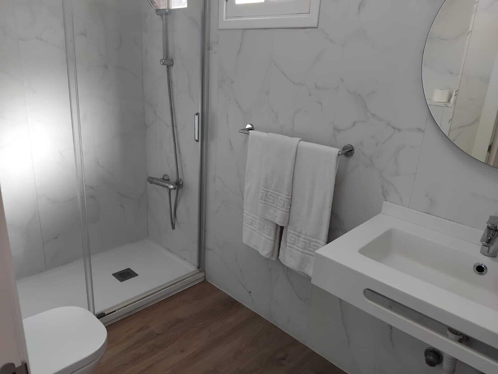 A bathroom with a shower, toilet, and sink.