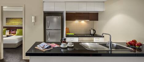 A modern kitchen with a black countertop, stainless steel appliances, and a sink.