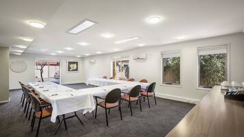 A conference room with long tables and chairs, white walls, and large windows.
