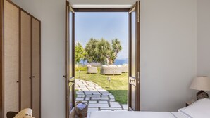 Een slaapkamer met uitzicht op een tuin en de zee.