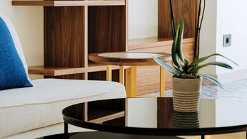 Una sala de estar moderna con un sofá blanco, una mesa de centro redonda negra y una estantería de madera.