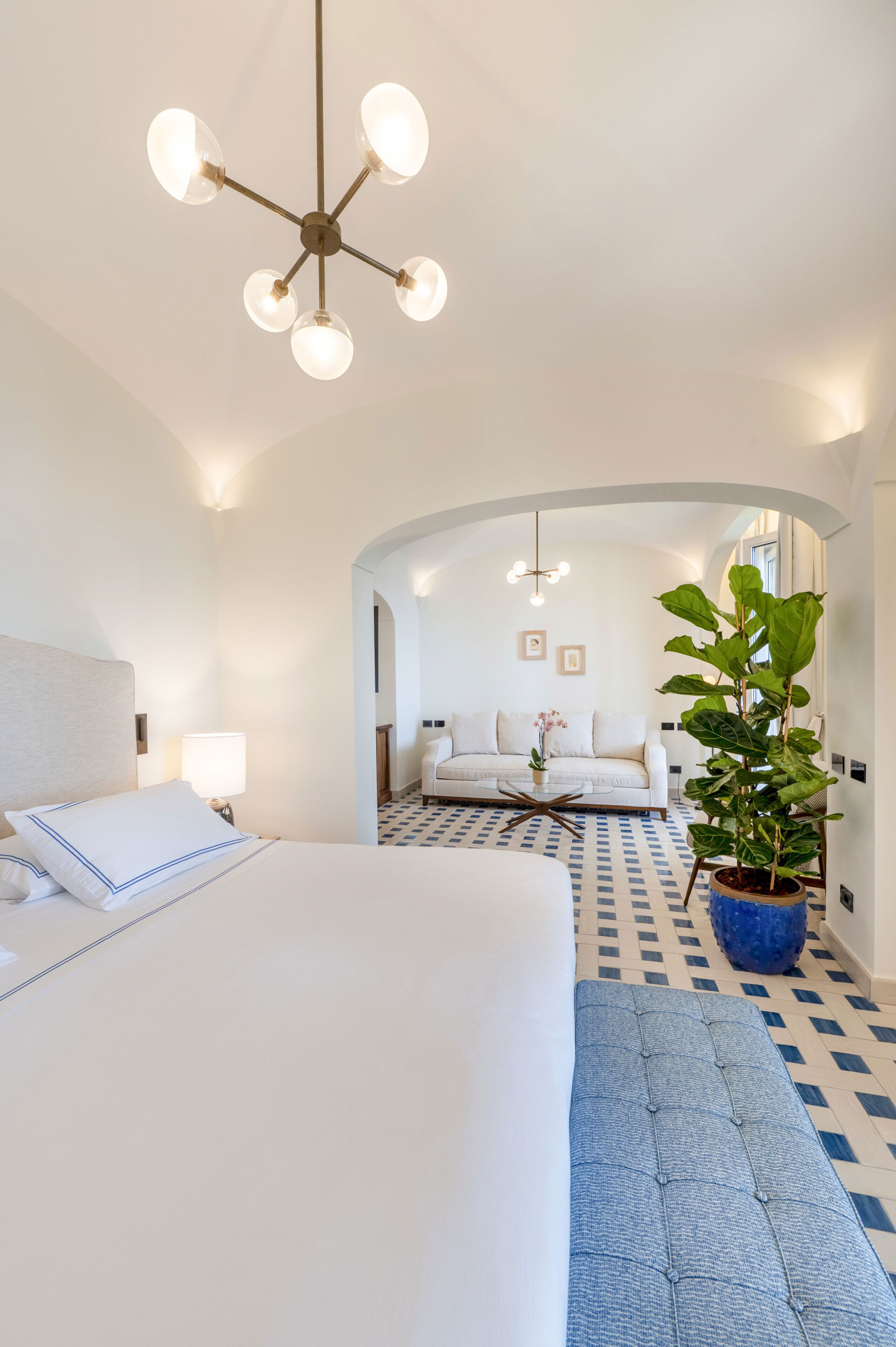 Een hotelkamer met een bed, een bank, een bijzettafeltje en een potplant.