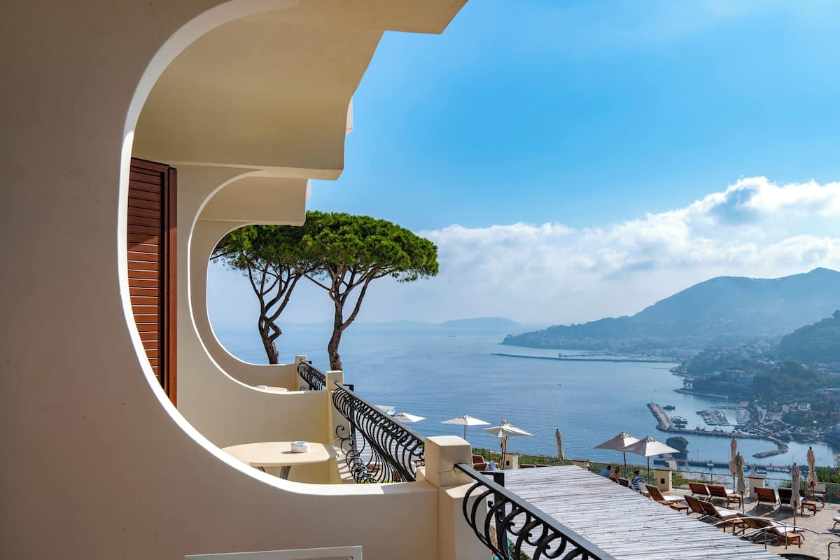 Ein Balkon mit Blick auf das Meer, einen Baum und ein Geländer.