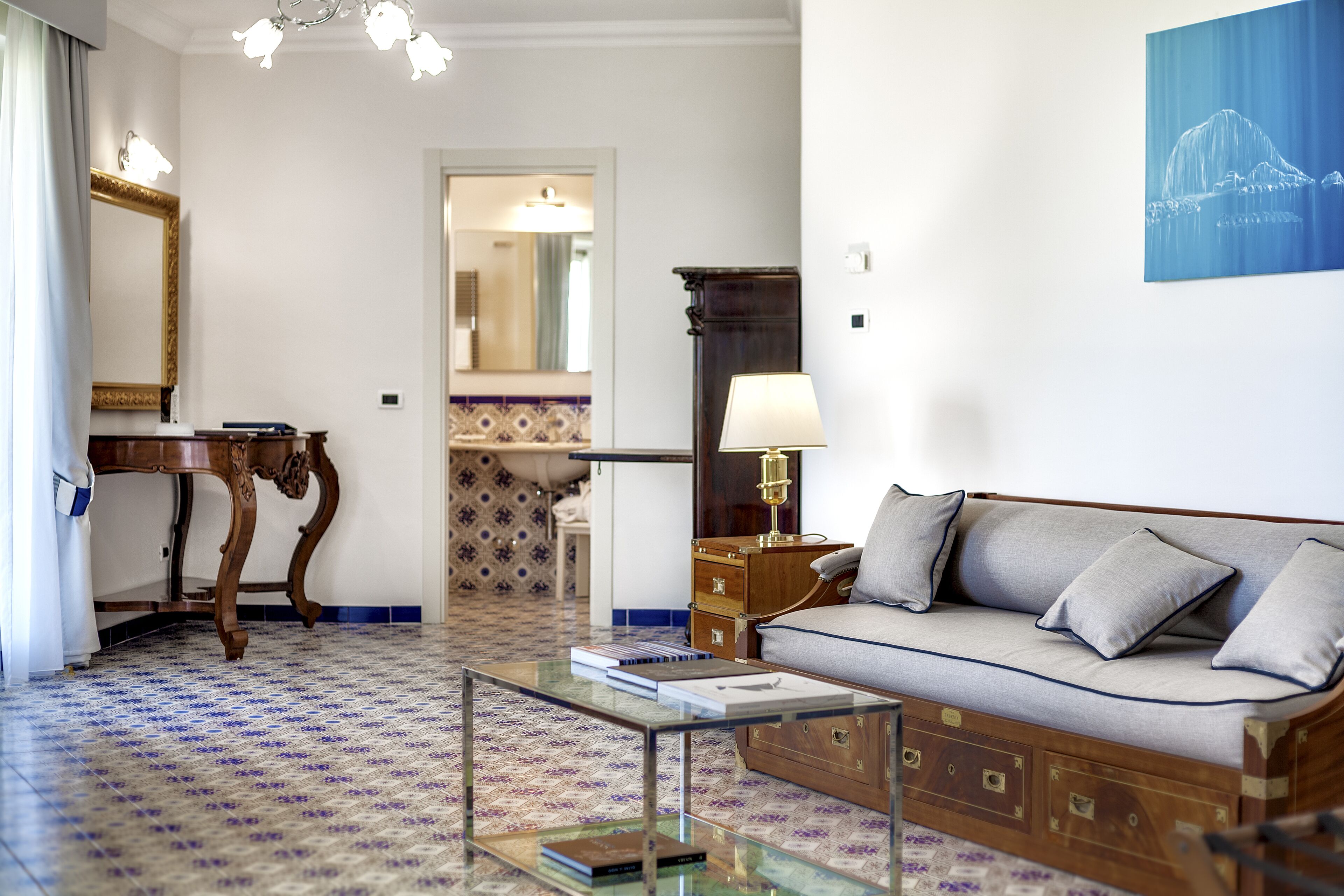 Una sala de estar con sofá, una mesa de centro de cristal, un aparador de madera y un espejo.