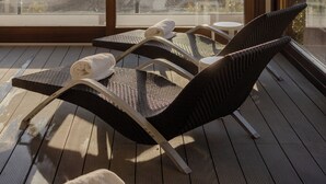 Een balkon met twee rieten lounge fauteuils, een kleine tafel en een handdoek.