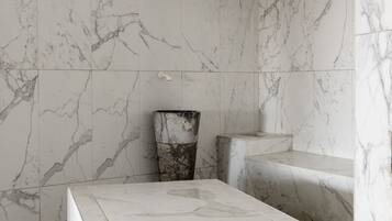 Une salle de bain moderne avec des murs en marbre et une colonne centrale.