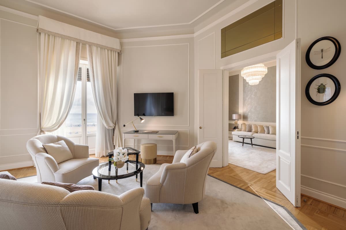 A spacious living room with a large window, a flat-screen TV, a round coffee table, and a sofa.