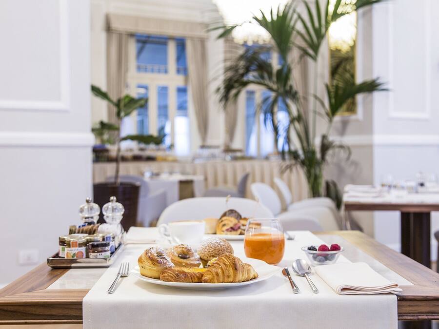 A breakfast table with pastries, a fruit bowl, and a glass of orange juice.
