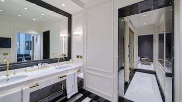 A luxurious bathroom with a double sink vanity, a large mirror, and a black and white marble floor.