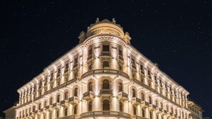 A grand, illuminated hotel with classical architecture, featuring a prominent entrance and multiple balconies.