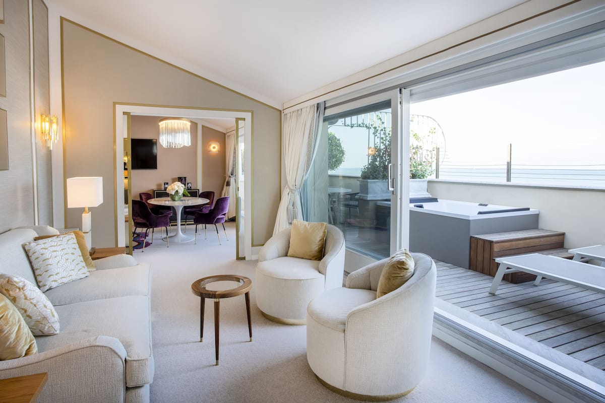 A modern living room with a sofa, armchairs, a coffee table, and a dining area with a table and chairs.