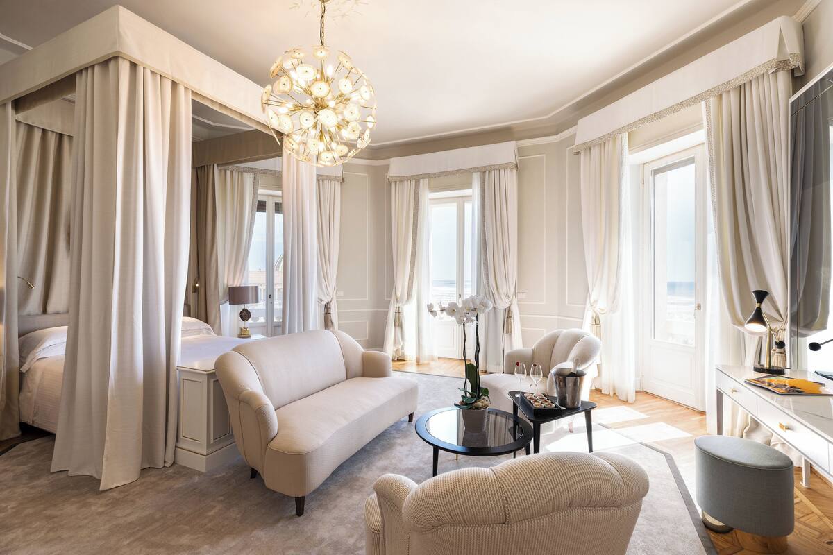 A spacious living room with a sofa, armchairs, a coffee table, and a chandelier.