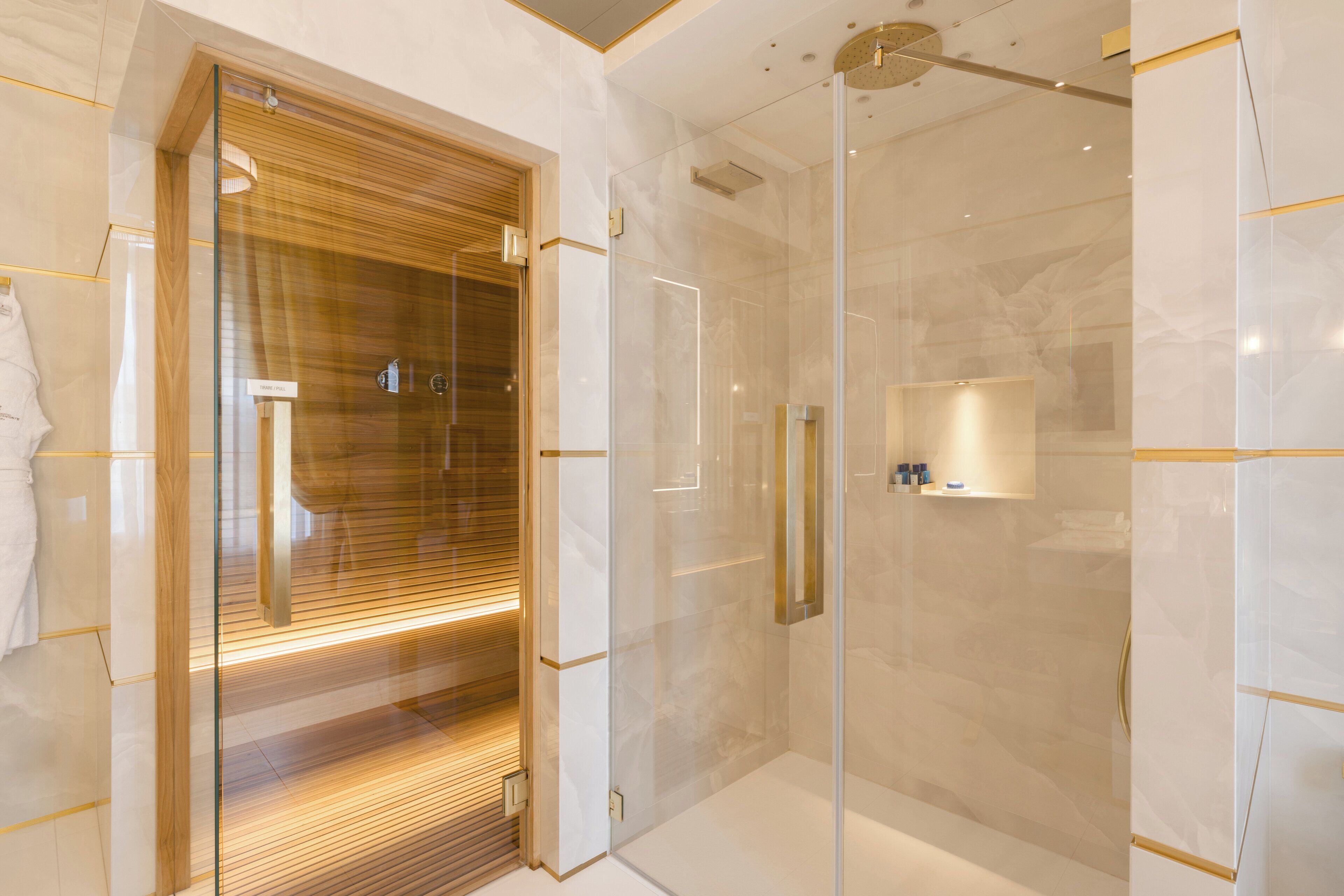 Un baño moderno con ducha de vidrio, tocador de madera y piso de mármol.