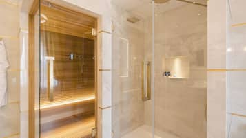 Un baño moderno con ducha de vidrio, tocador de madera y piso de mármol.