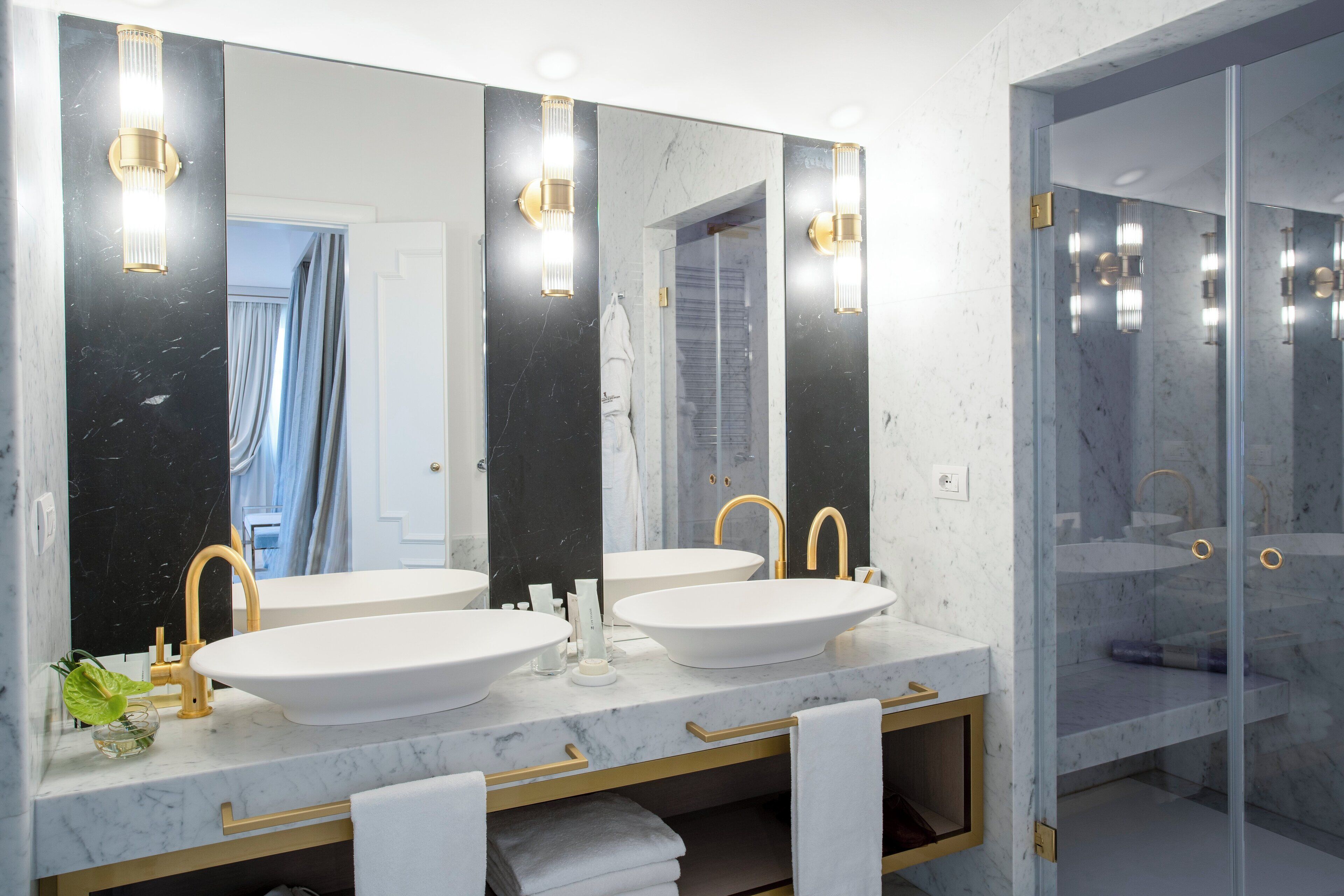 A bathroom with two sinks, a large mirror, and a glass shower enclosure.