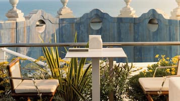 Une terrasse avec vue sur la mer, comprenant une table et deux chaises.