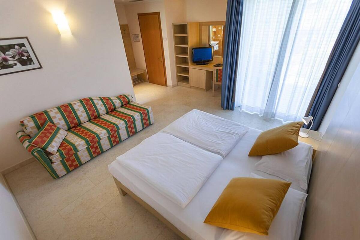 Une chambre d’hôtel équipée d’un lit, d’un canapé, d’un bureau avec un ordinateur et d’une télévision.
