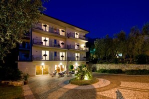 A multi-story hotel with outdoor seating and a landscaped courtyard. - Hotel Garni Orchidea (Malcesine)