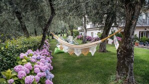 Una hamaca en un jardín con árboles y flores moradas.