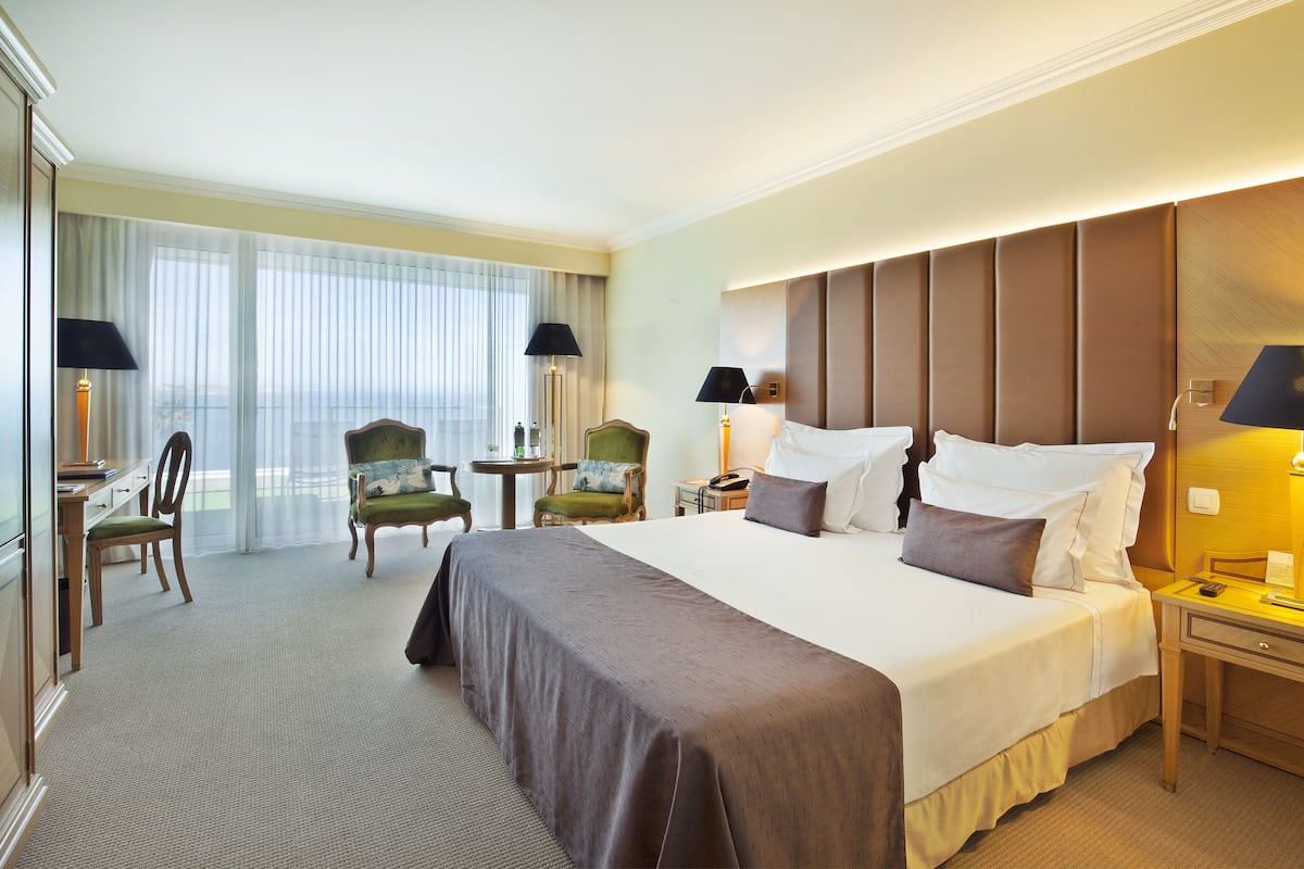 Una habitación de hotel con una cama grande, dos sillas, un escritorio y vistas al exterior.