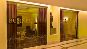 Ingresso di un hotel con un cartello 'BUSINESS', una statua e un interno moderno visibile attraverso le porte in vetro.