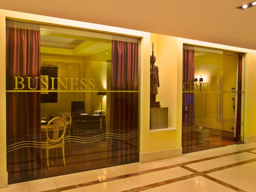 Entrada de hotel con un cartel que dice 'BUSINESS', una estatua y un interior moderno visible a través de las puertas de vidrio.