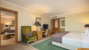 Quarto de hotel com cama, escrivaninha, cadeira e televisão.