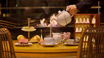 Una mesa dispuesta con tetera, tazas, un pastel pequeño y una exhibición de velas.