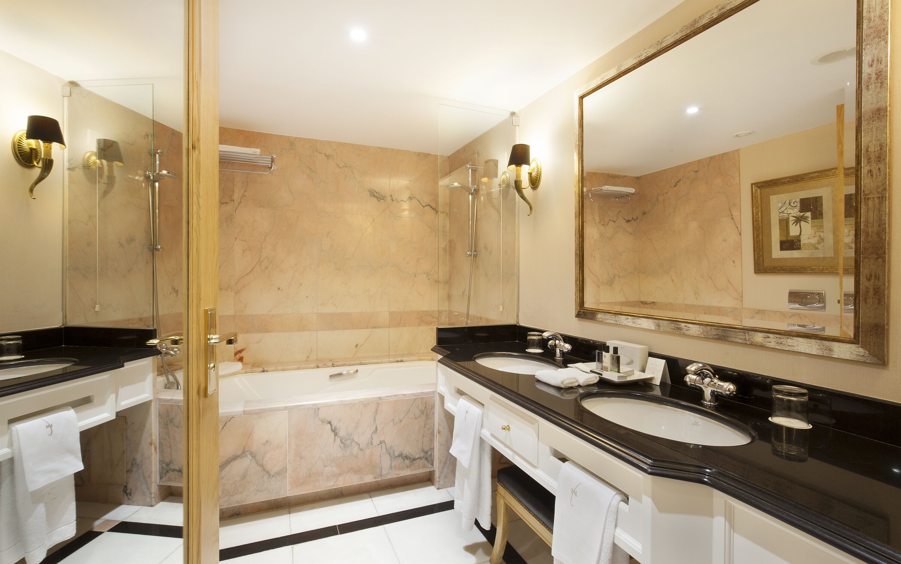 Un baño moderno con dos lavamanos, una bañera y una ducha con cerramiento de vidrio.