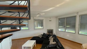 Una sala de estar moderna con un sofá seccional negro, una mesa de centro blanca y una escalera de madera.