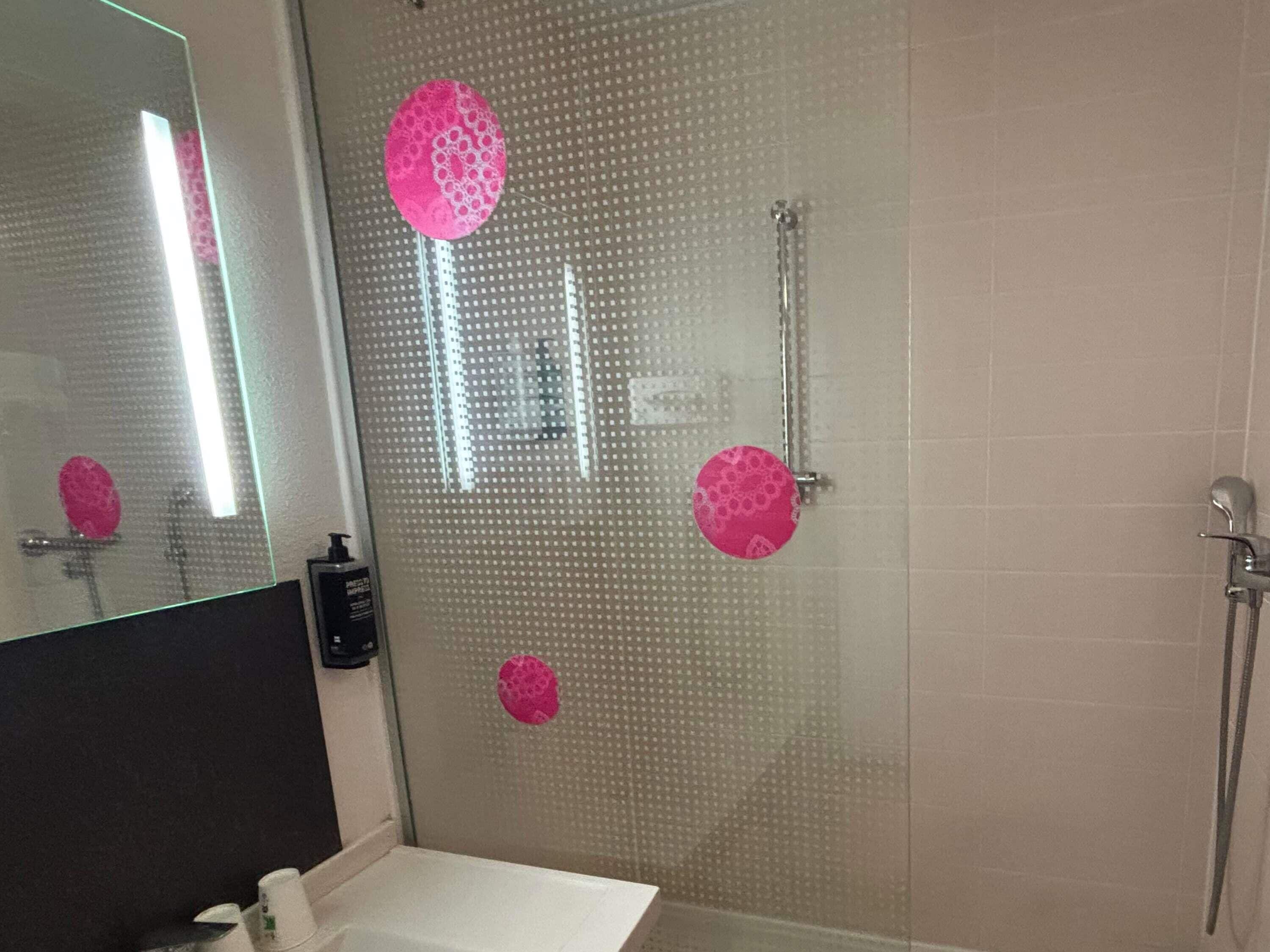 Een douche met glazen deur, een wastafel en een spiegel.