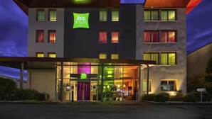 Un moderno edificio de hotel con un llamativo letrero de 'ibis Styles Hotels', ventanas amplias y una zona de entrada cubierta.