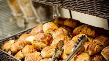 A display of assorted pastries in wicker baskets with tongs.