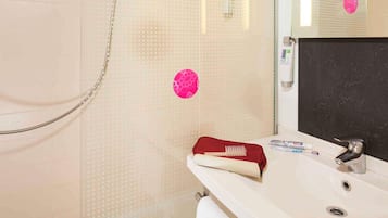 A bathroom with a shower, a sink, and a mirror.