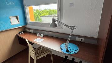 A compact room with a desk, chair, and a window with a view of greenery.