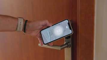 Een hand vasthoudt een smartphone met een vergrendelscherm waarop een slotpictogram en een camera-pictogram staan.