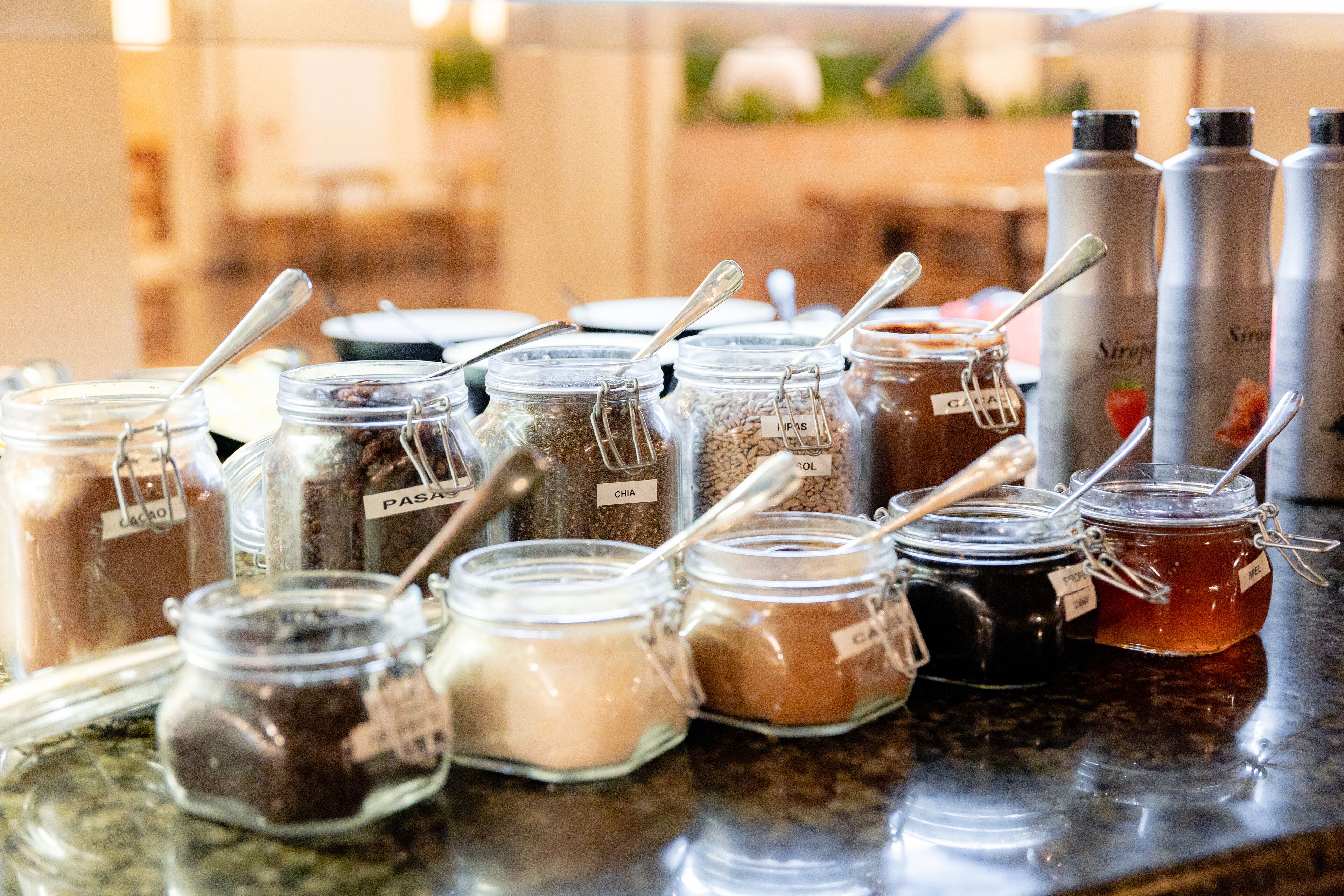 A variety of food items in jars with spoons, including labels like "Cacao" and "Chia".